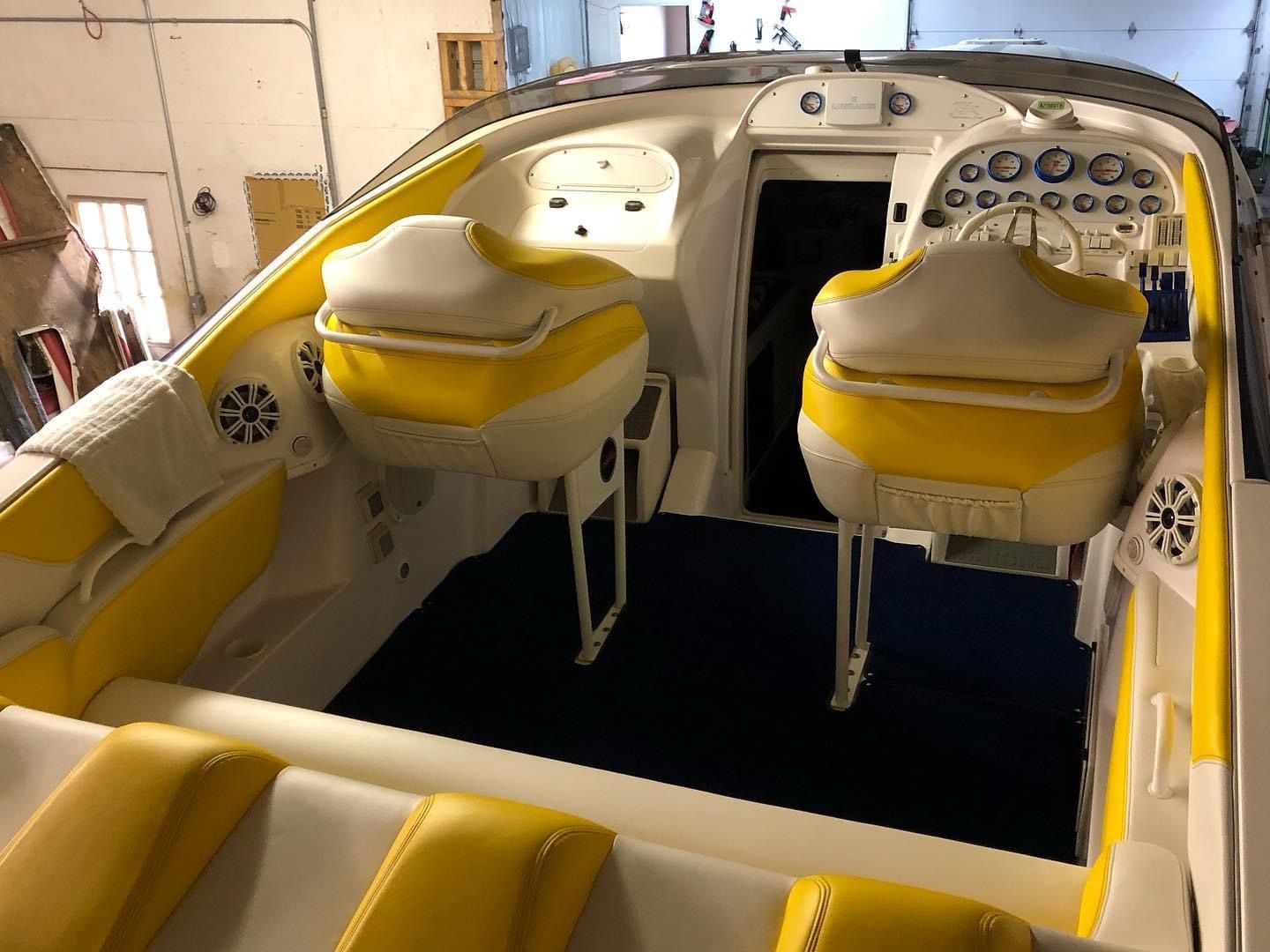 Interior of a yellow and white speedboat with two bucket seats and a rear bench seat.