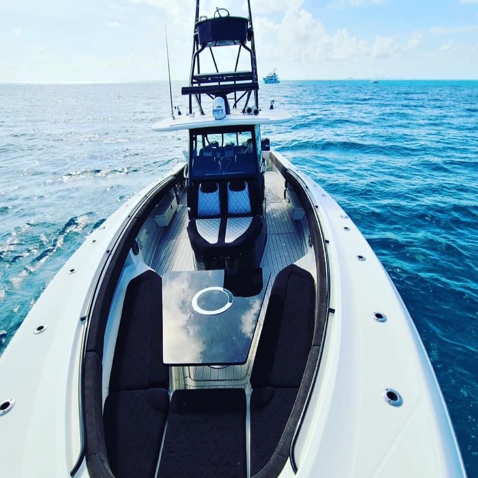 White motorboat on ocean, open deck, center console with black seats, clear blue water.