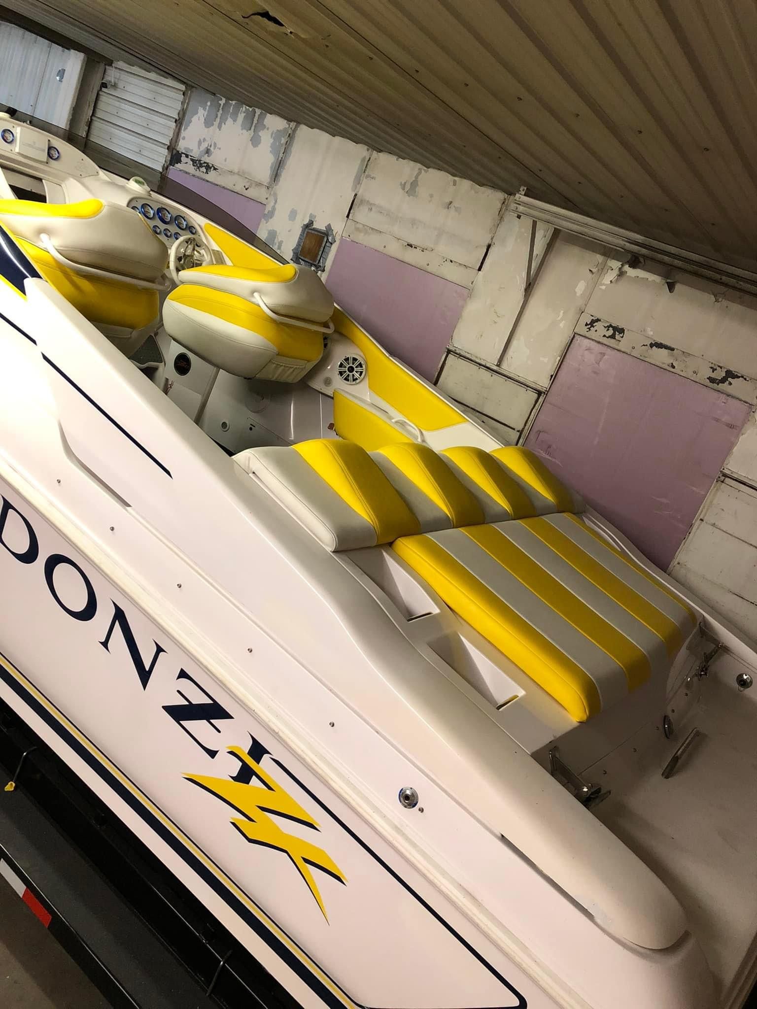 White and yellow Donzi boat interior with seating, stored in a garage.