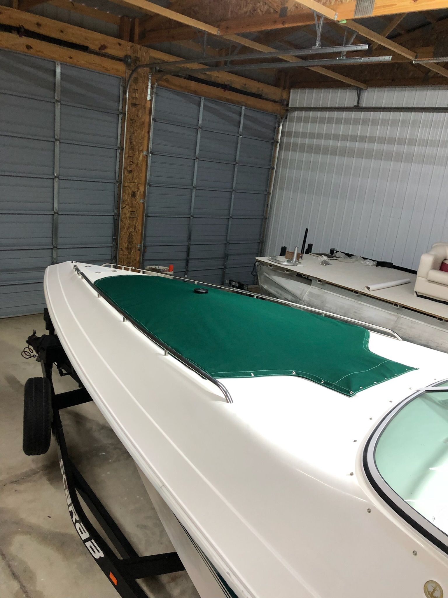 A white boat with a green cover inside a garage.