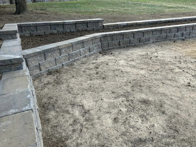 Retaining walls made of gray blocks separate two levels of soil.