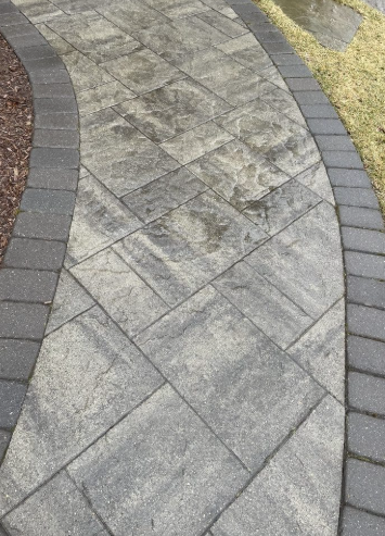 Stone paver walkway with dark border, curving through grass.