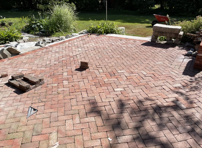 Red brick patio with herringbone pattern, partially completed. Bricks and small