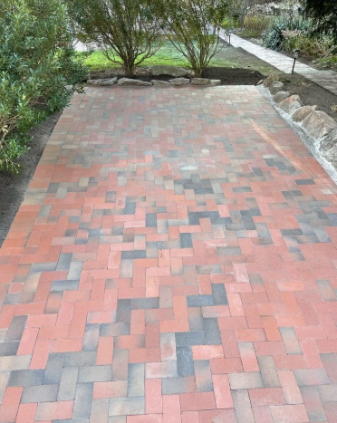 Brick patio with a herringbone pattern of red and gray bricks.