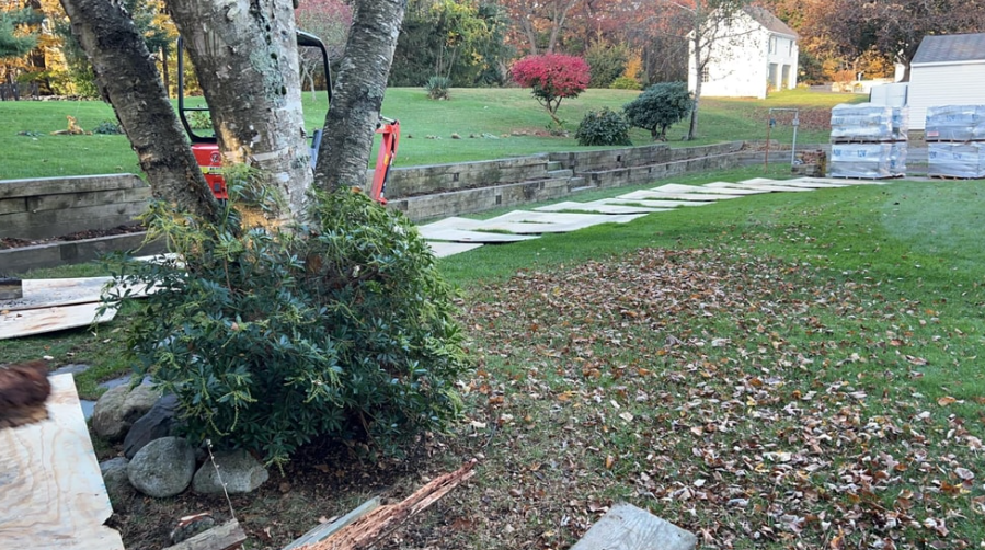 Backyard with a lawn, stone walkway, stone wall