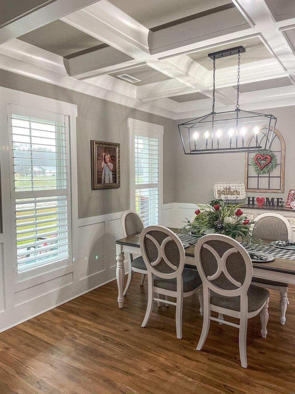 Dining room with white shutters, a coffered ceiling, a chandelier, and a table set for dining.