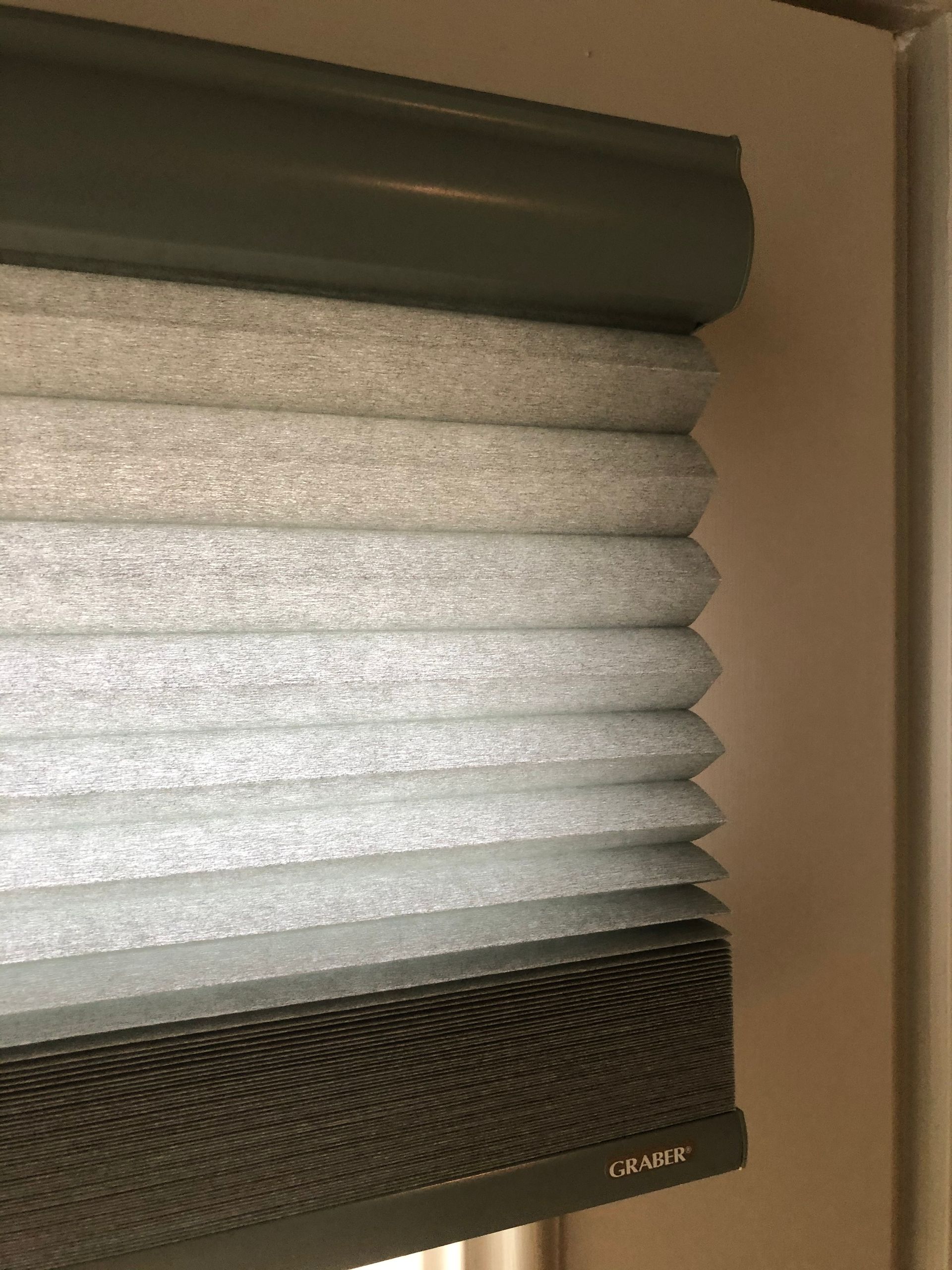 Gray and white cellular shade window blinds are partially lowered.