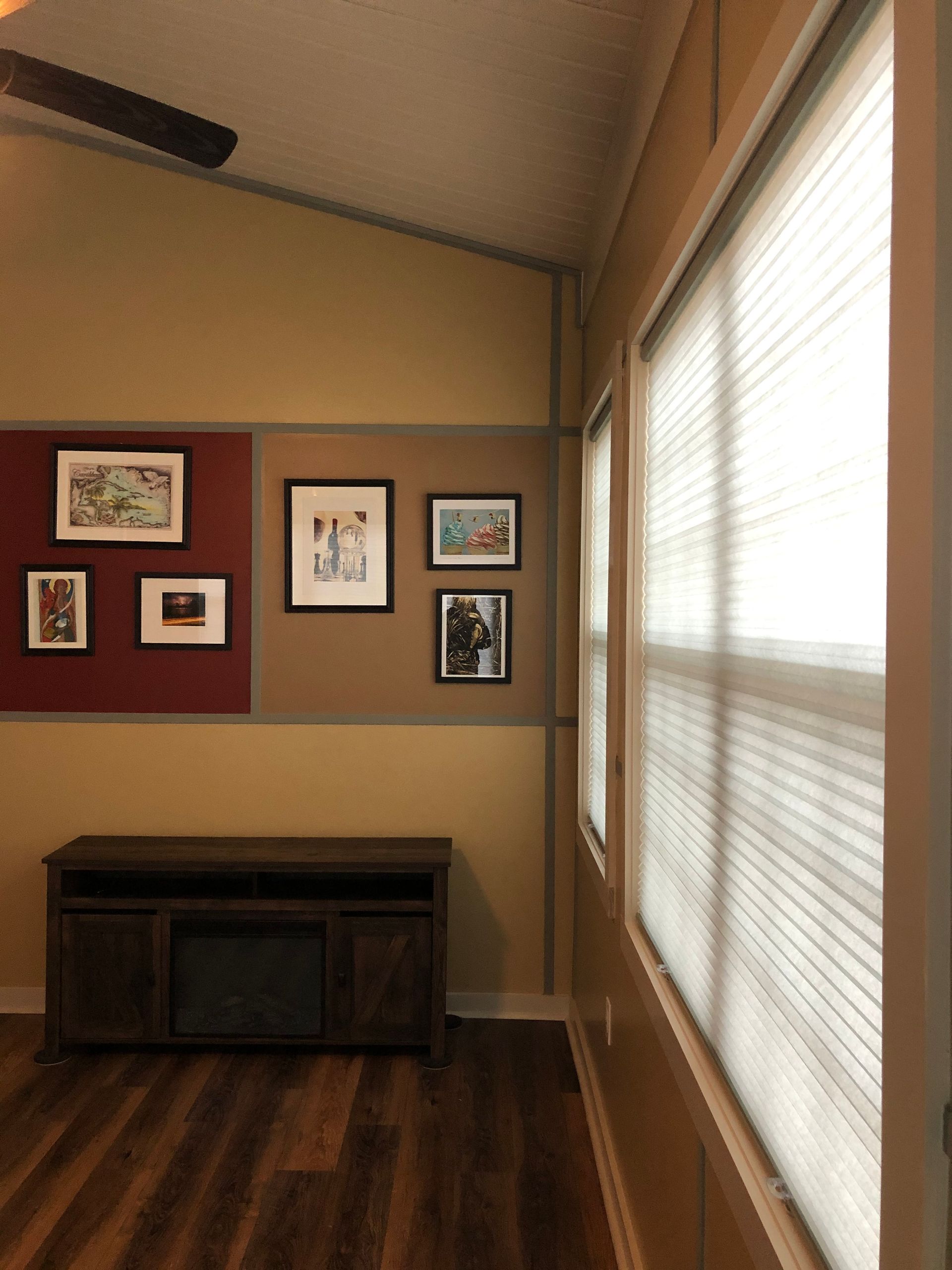 Room interior with artwork on the wall, a media cabinet, and a window with blinds.