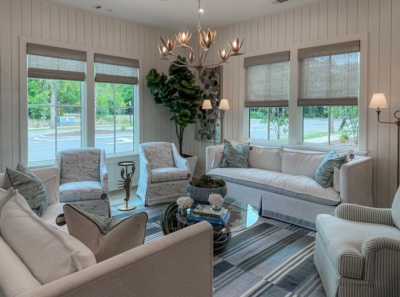 Cozy living room with white walls, natural light, blue and white accents, and a floral chandelier.