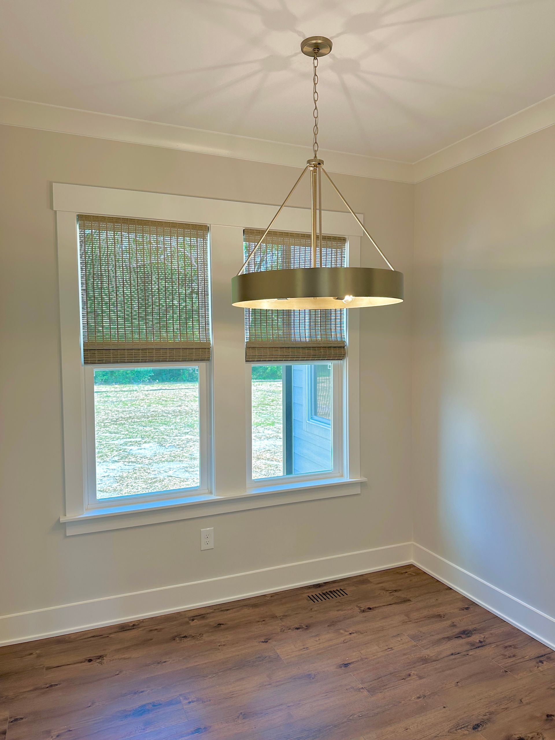Dining room with windows, wood blinds, and a chandelier; light-colored walls and wood flooring.