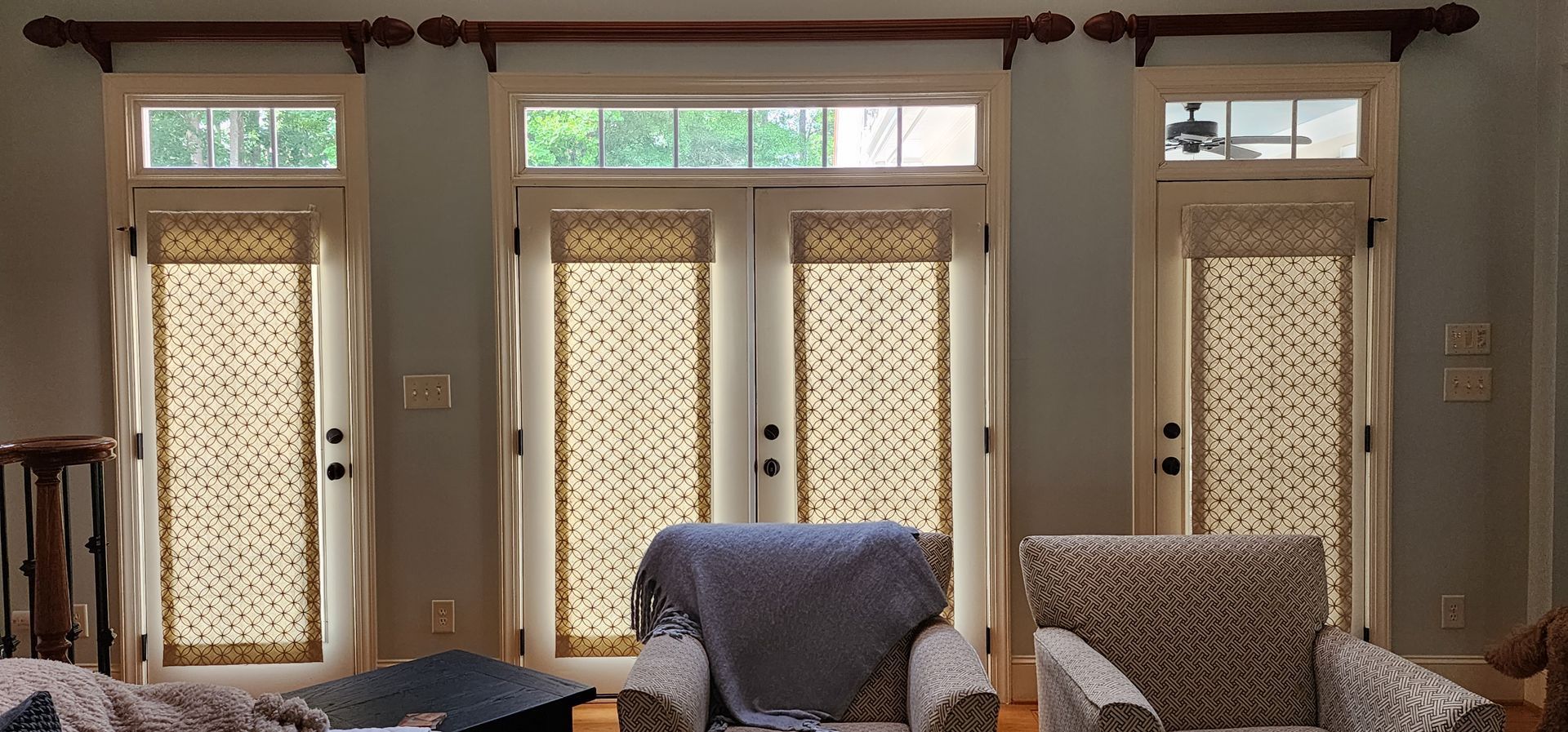 Three French doors with blinds, curtain rod, and two armchairs.