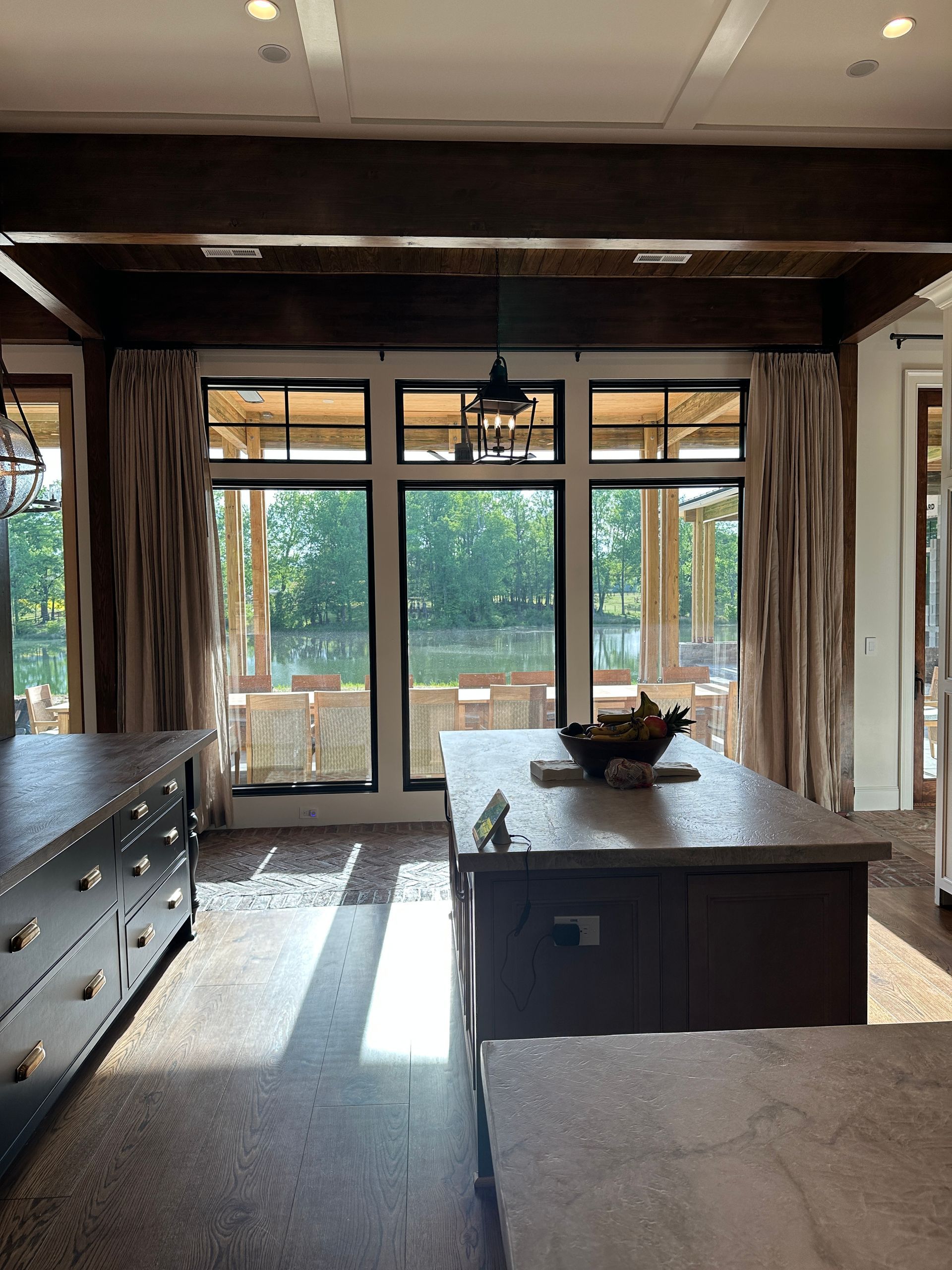 Kitchen interior with dark cabinetry, concrete countertops, and large windows overlooking a lake.