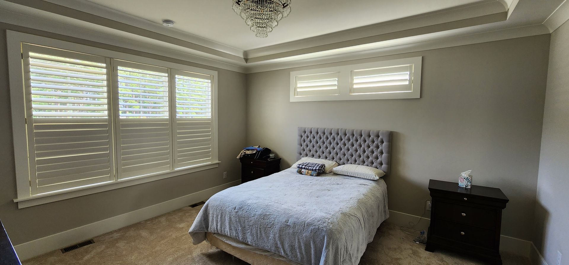Bedroom with bed, nightstand, and window with shutters.