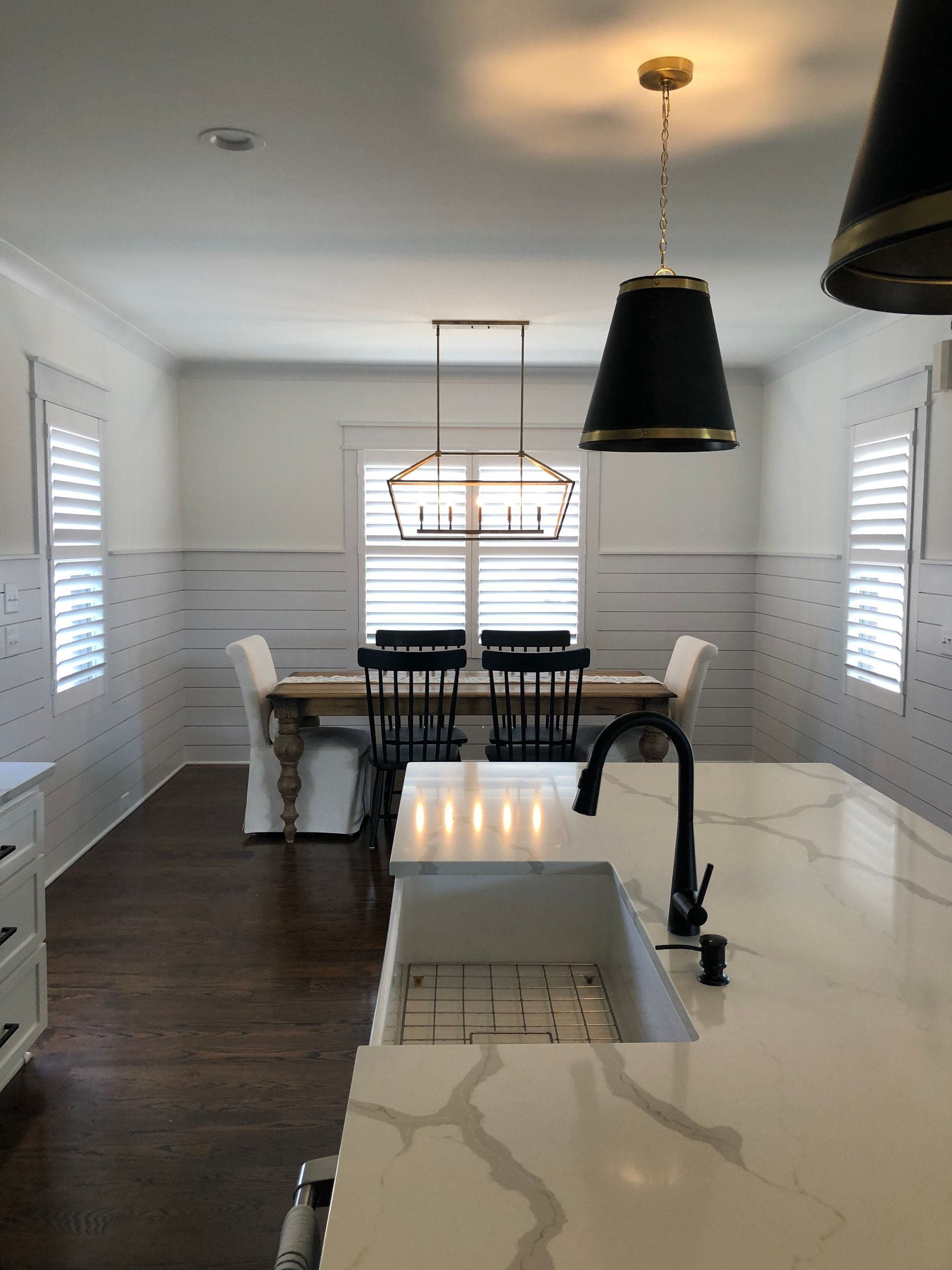 Kitchen with dark wood floors, white cabinets, and a long wooden dining table with black chairs.
