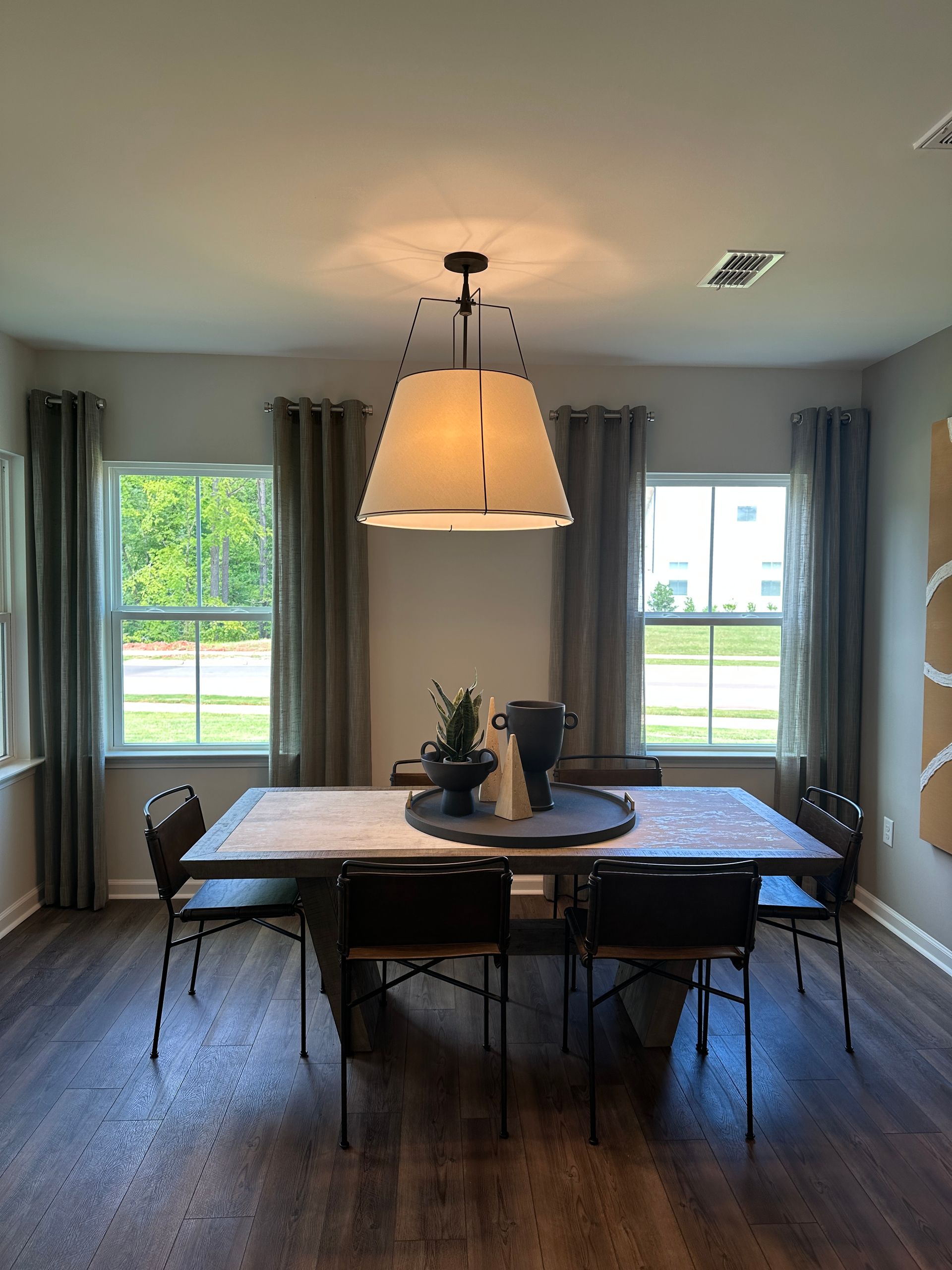 Dining room with a table, chairs, windows, and a hanging light fixture.