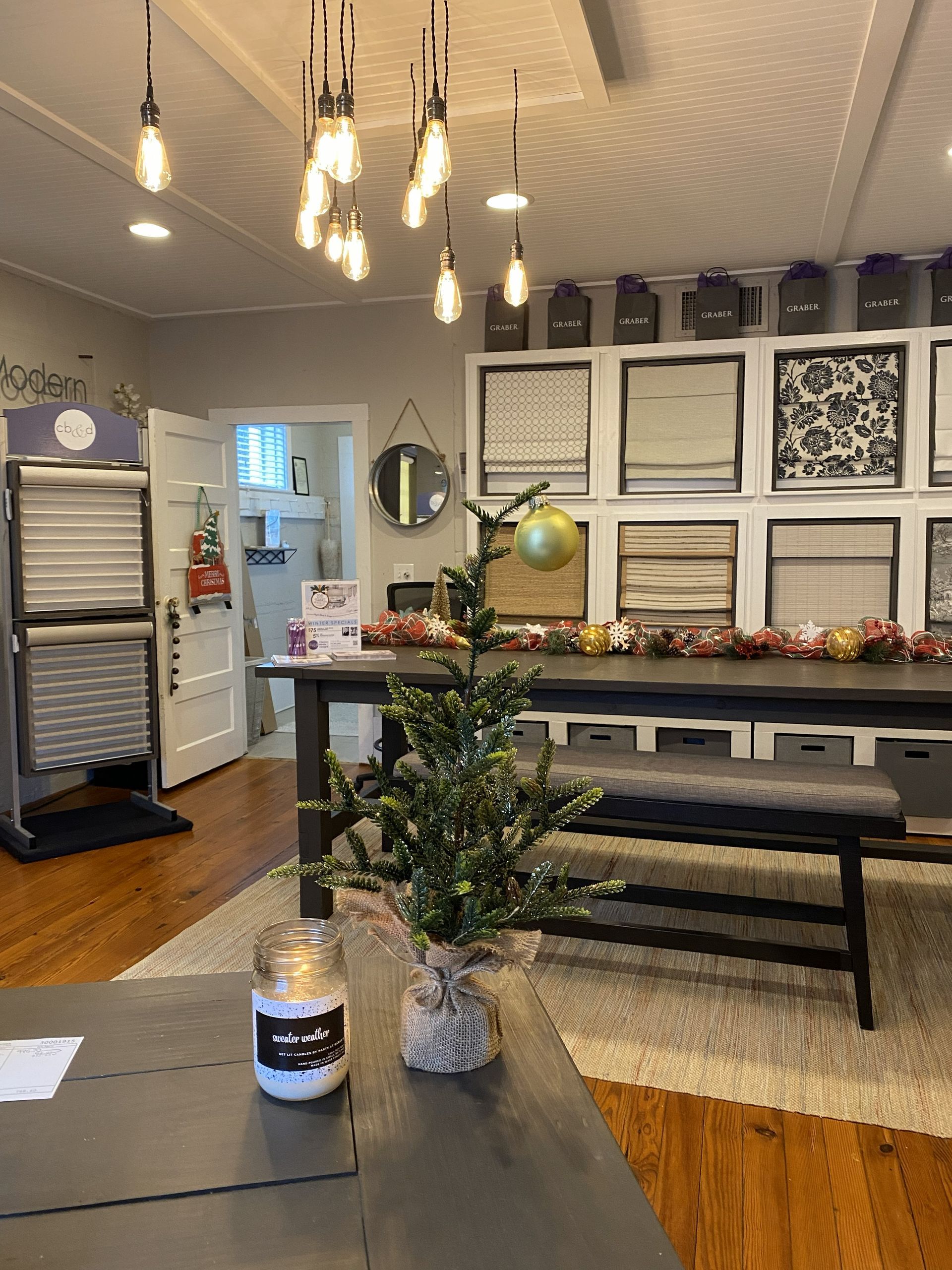 Interior of a room with a Christmas tree, hanging lights, and samples on display.