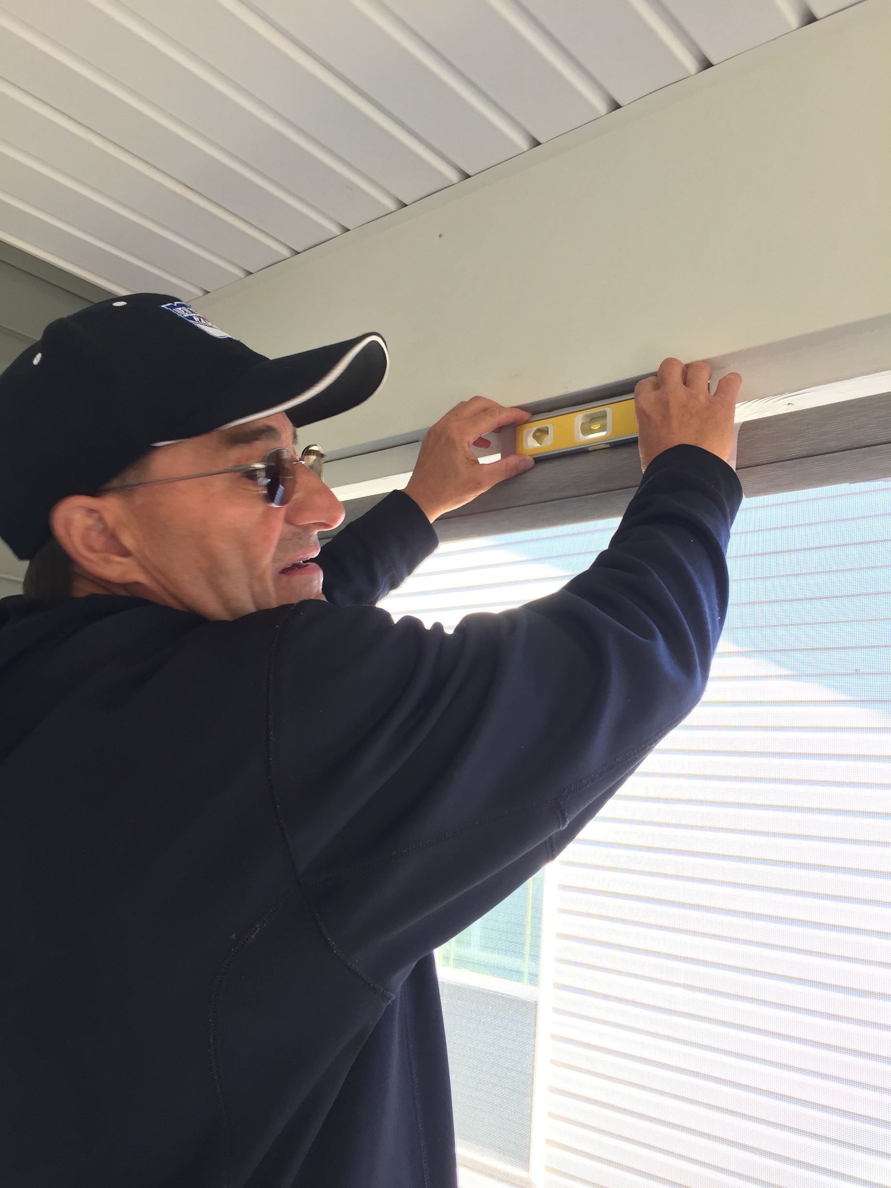 Person using a level on a window frame, likely installing something.