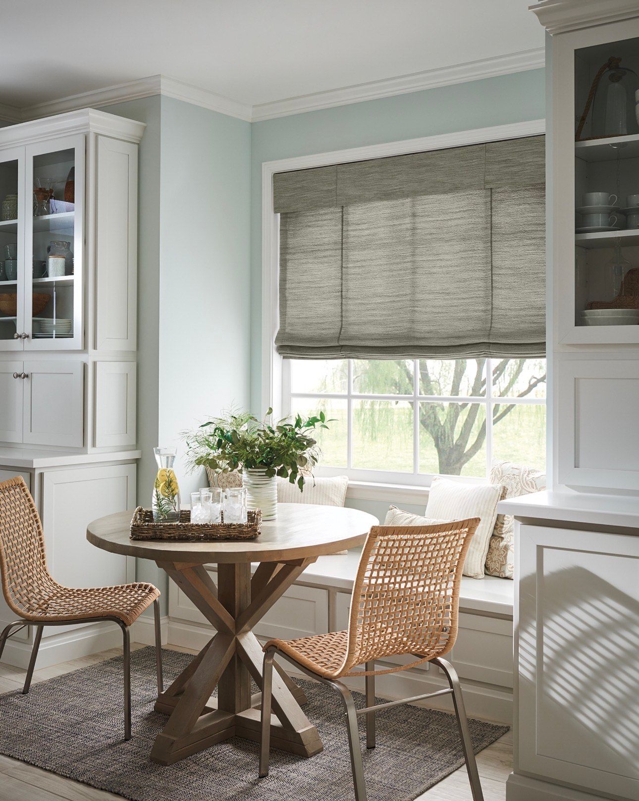 Kitchen dining nook with round table, woven chairs, and light blue walls.