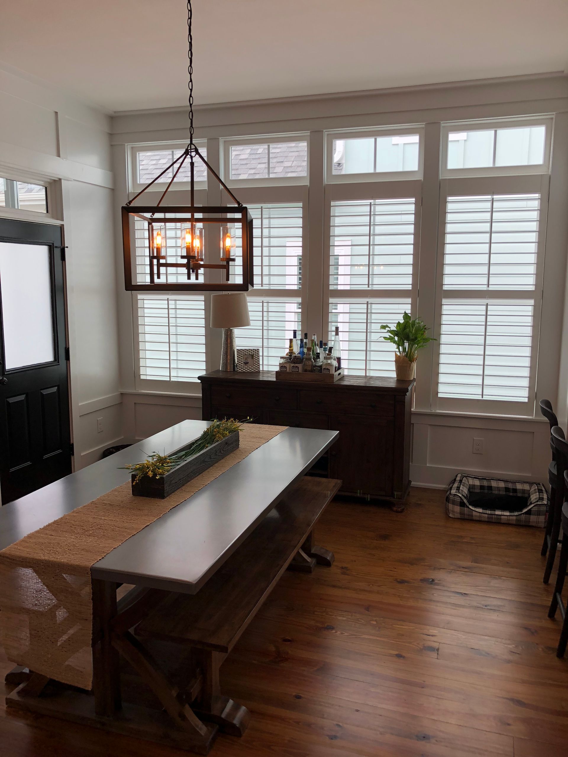 Dining room with wooden table, benches, and a dark cabinet near a window with blinds.