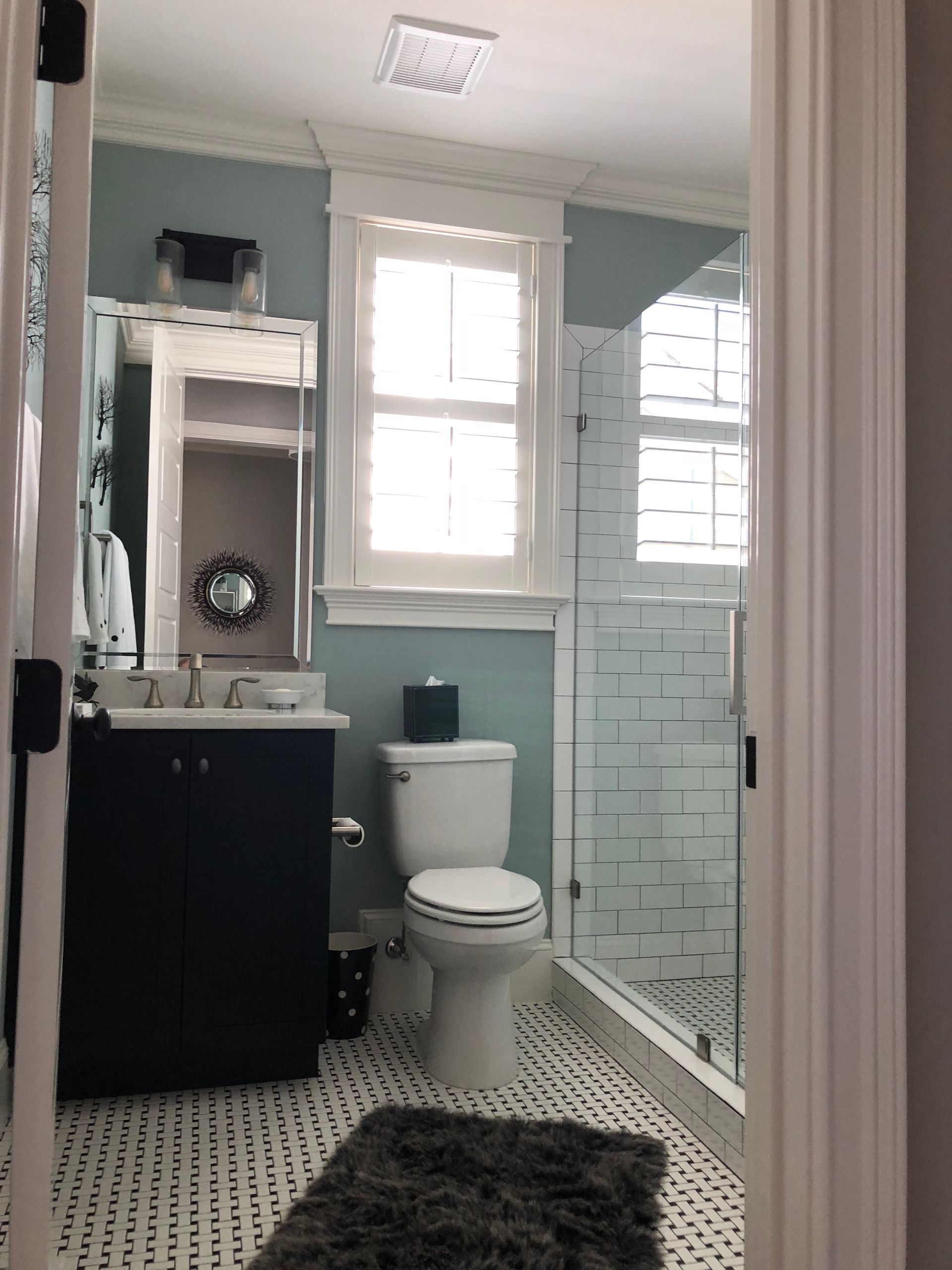 Bathroom interior with blue walls, white trim, shower, and black vanity.