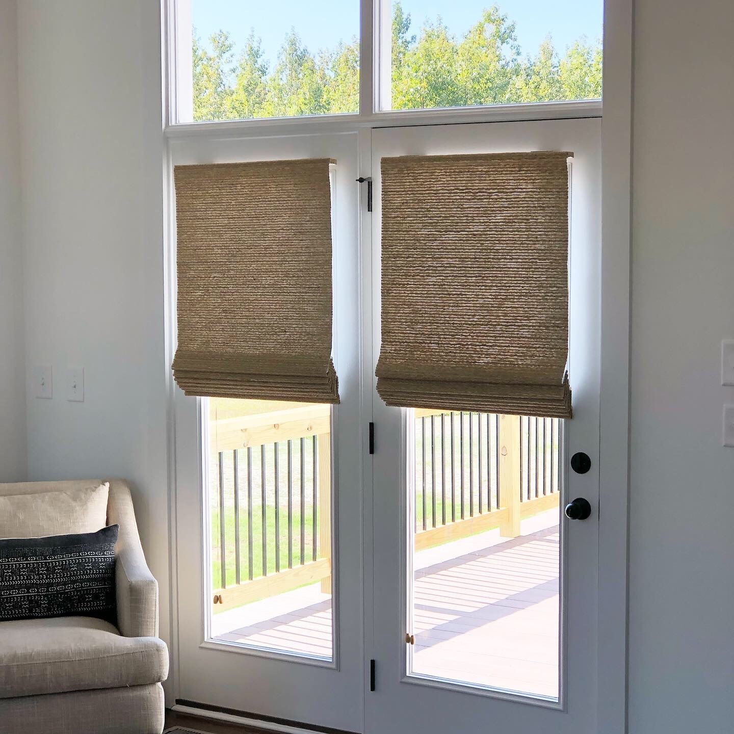 Two glass doors with shades, overlooking a deck. An armchair is on the left.