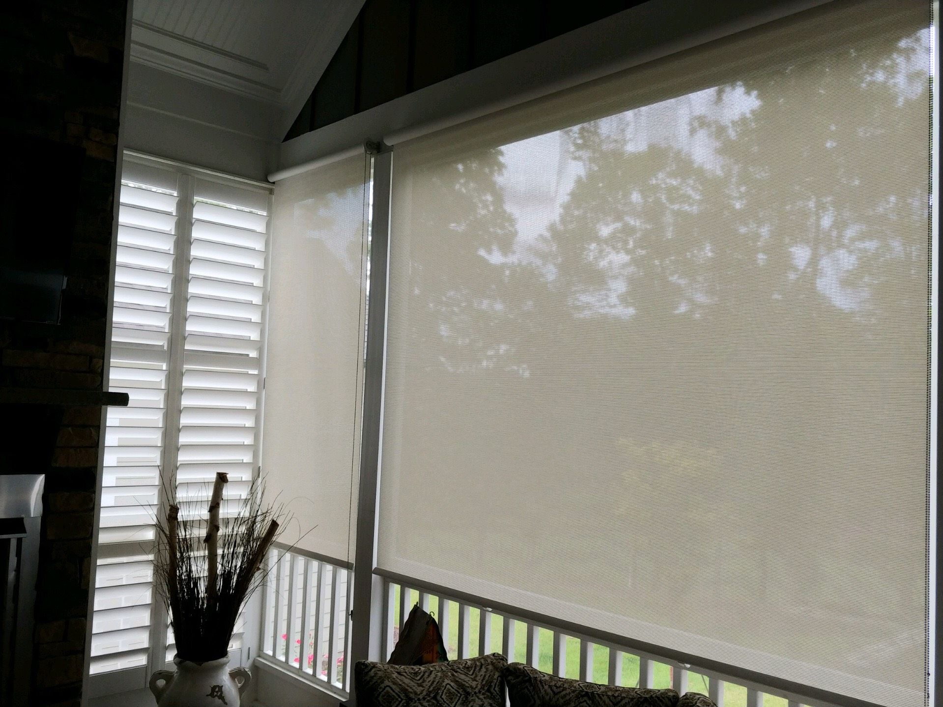 Covered porch with open roller shades and shuttered windows; interior view.
