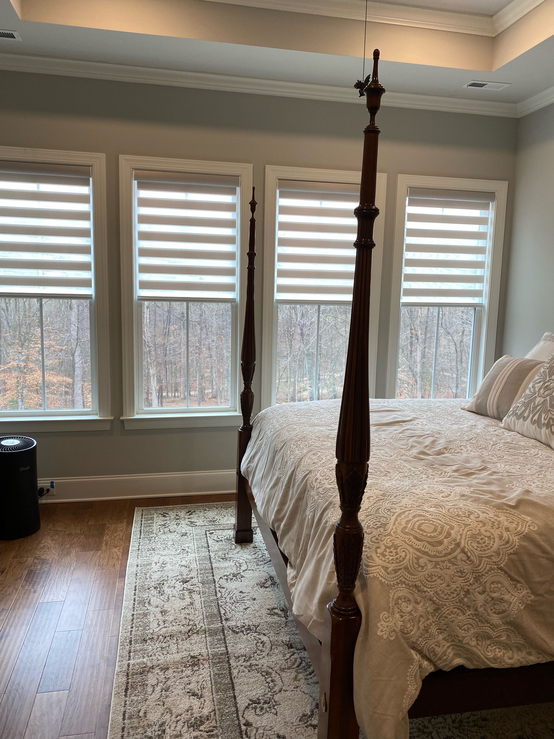 Bedroom with a bed, windows with blinds, and a rug on the hardwood floor.