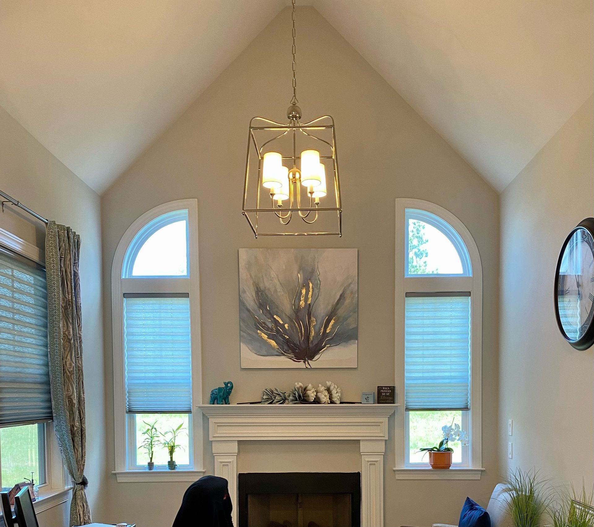Living room with a fireplace, arched windows, and a chandelier.