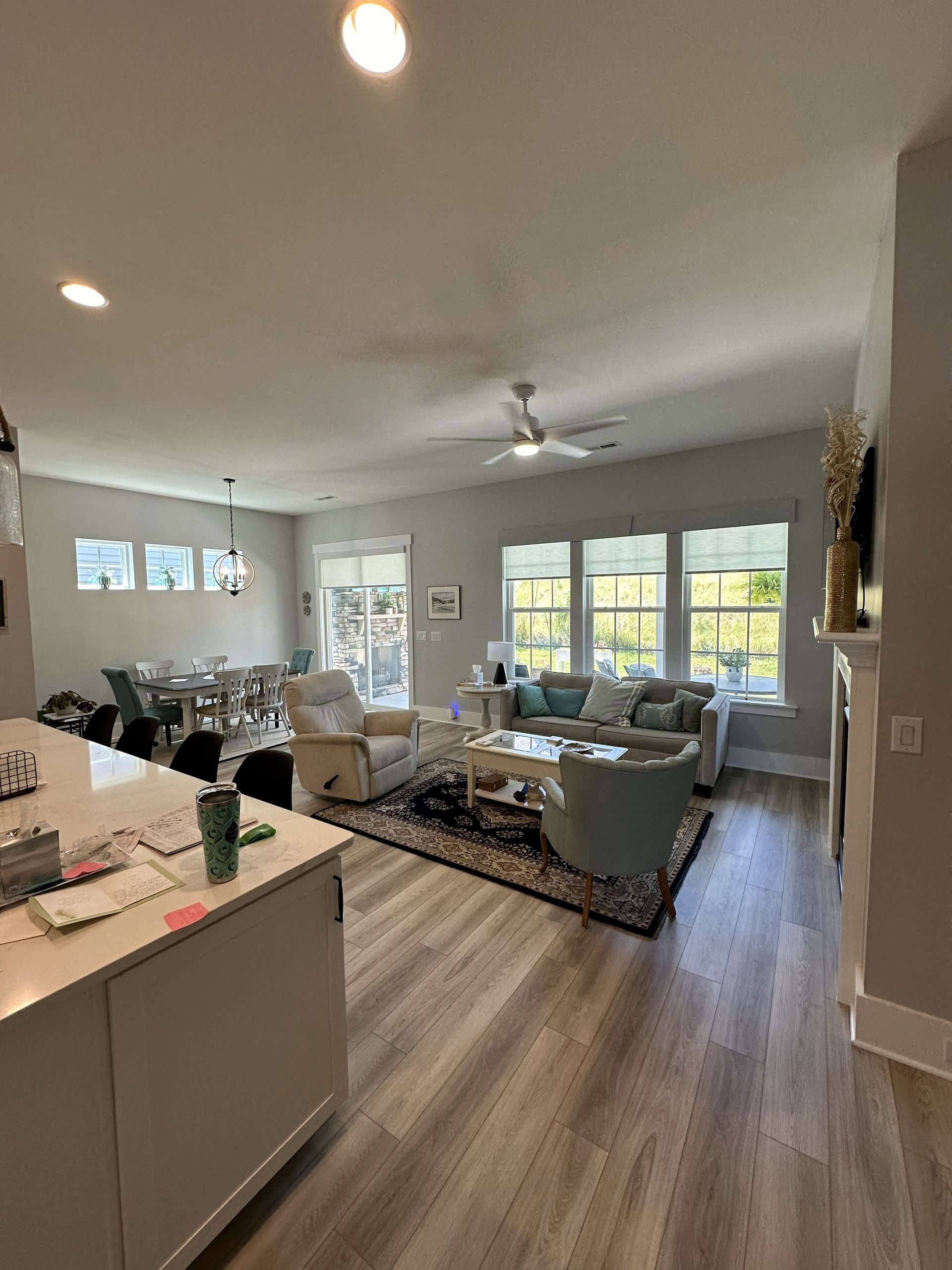 Open-plan living space with kitchen island, dining table, seating area with sofa, and windows.