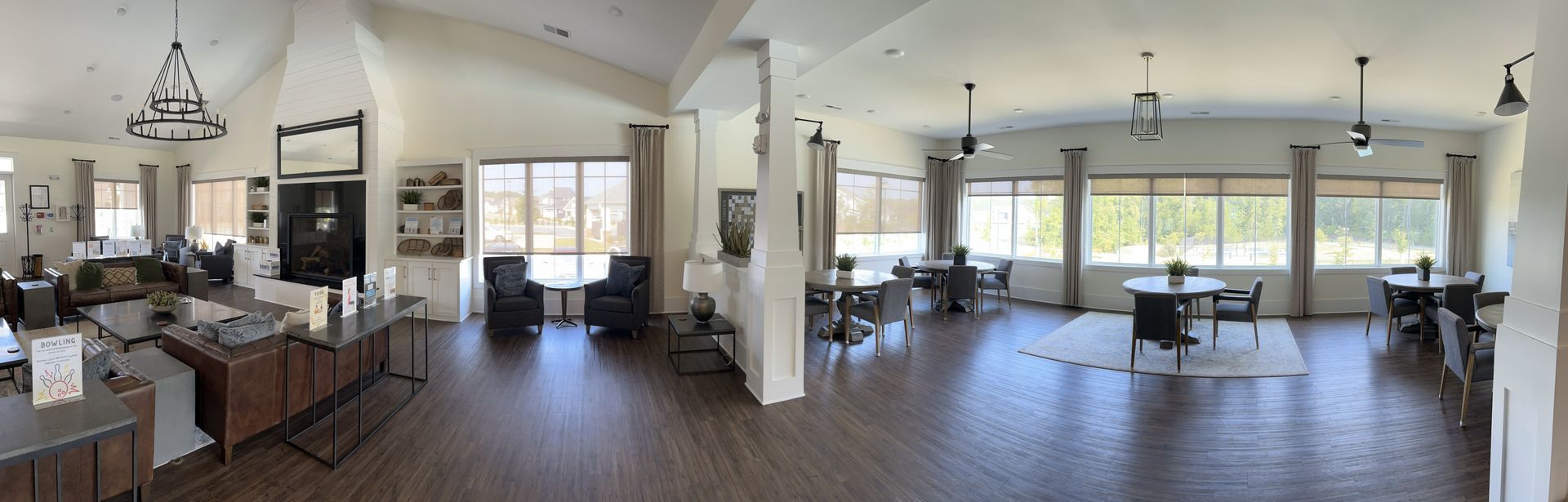Spacious, well-lit interior with tables, chairs, and couches. Large windows offer views.