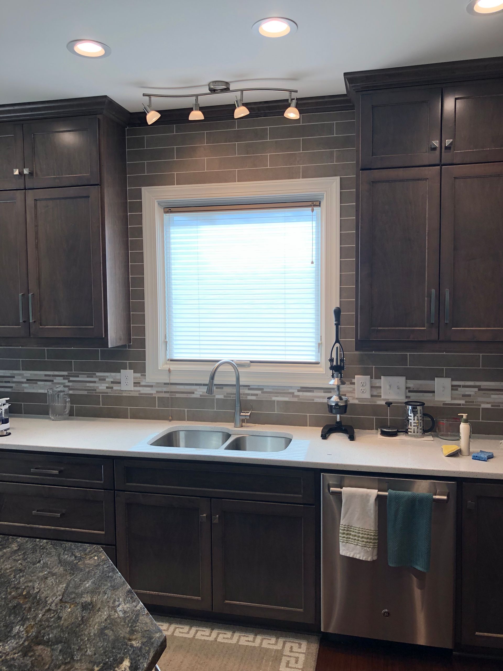 Kitchen with dark brown cabinets, white countertops, stainless steel appliances, and a window with blinds.