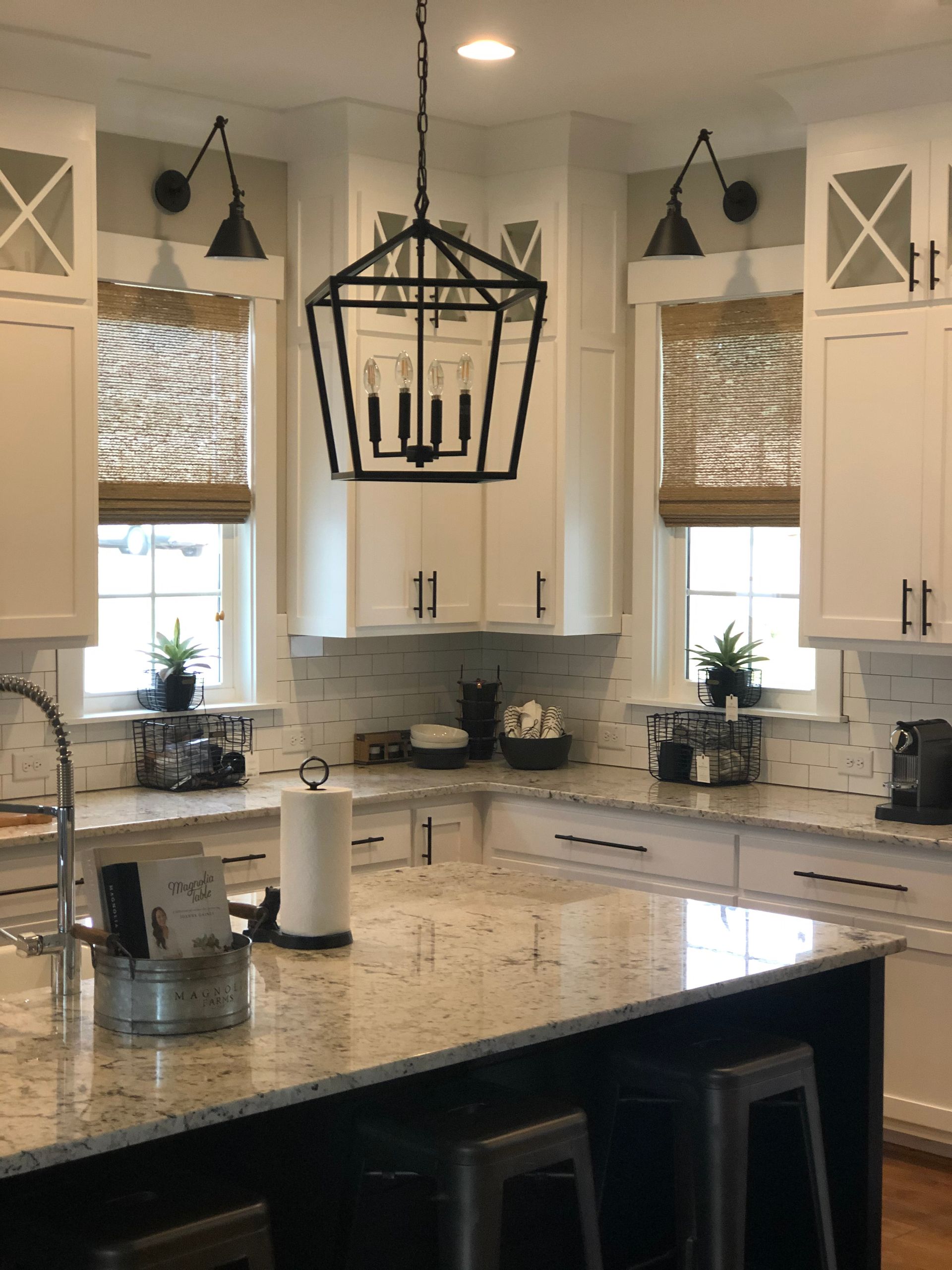 White kitchen with granite countertops, a large island, and a geometric chandelier.