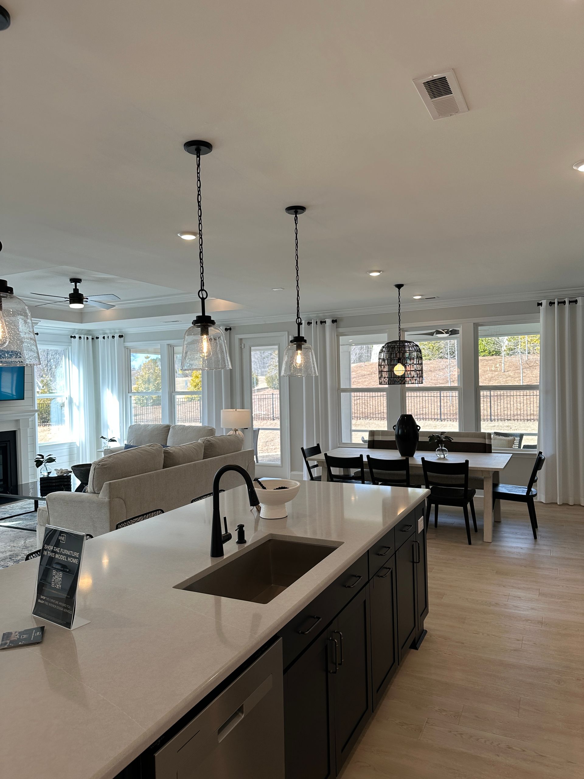 Modern kitchen with island, sink, pendant lights, and dining area with table and chairs.
