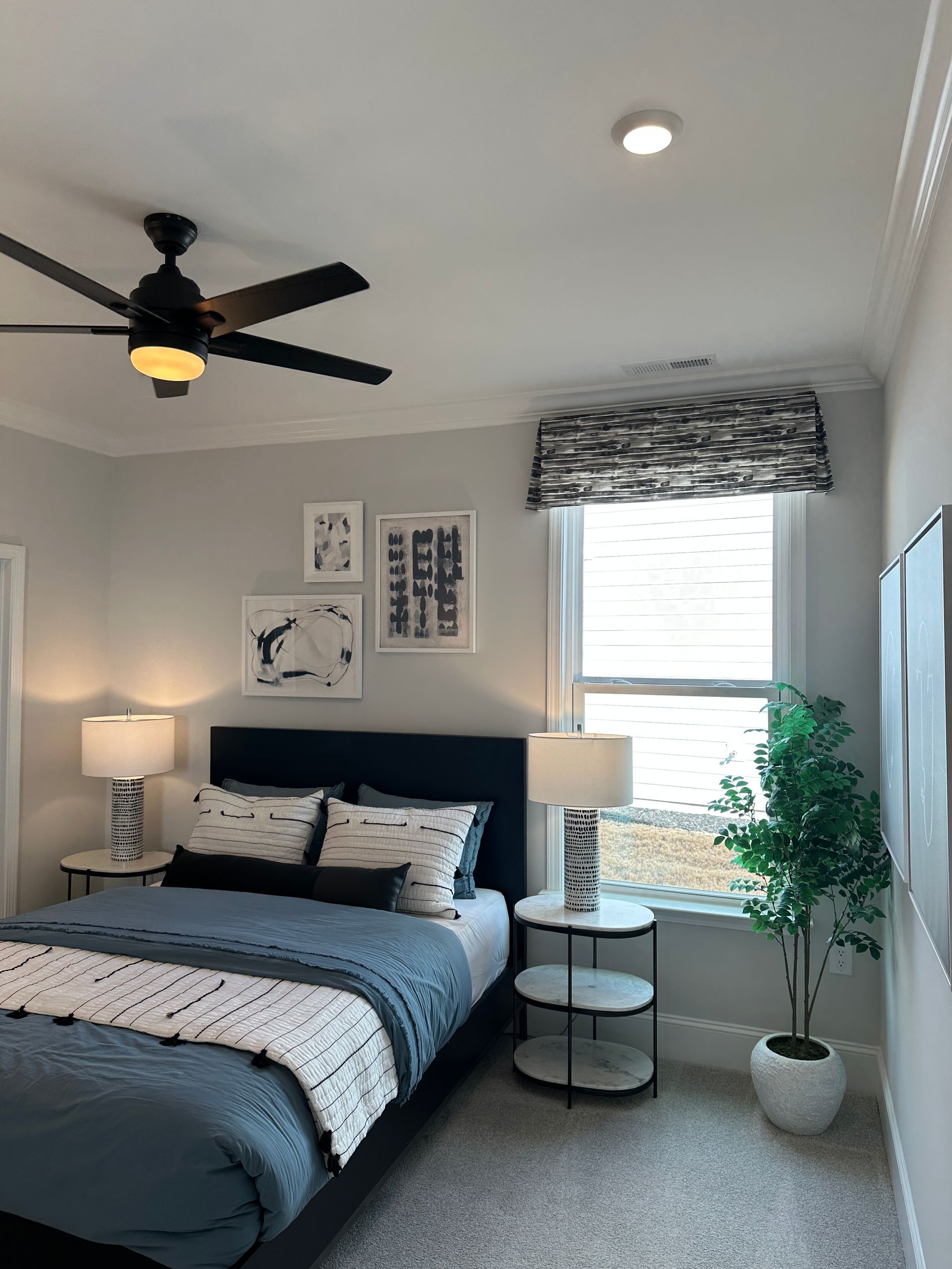 Bedroom with bed, nightstands, window, art, and a ceiling fan.