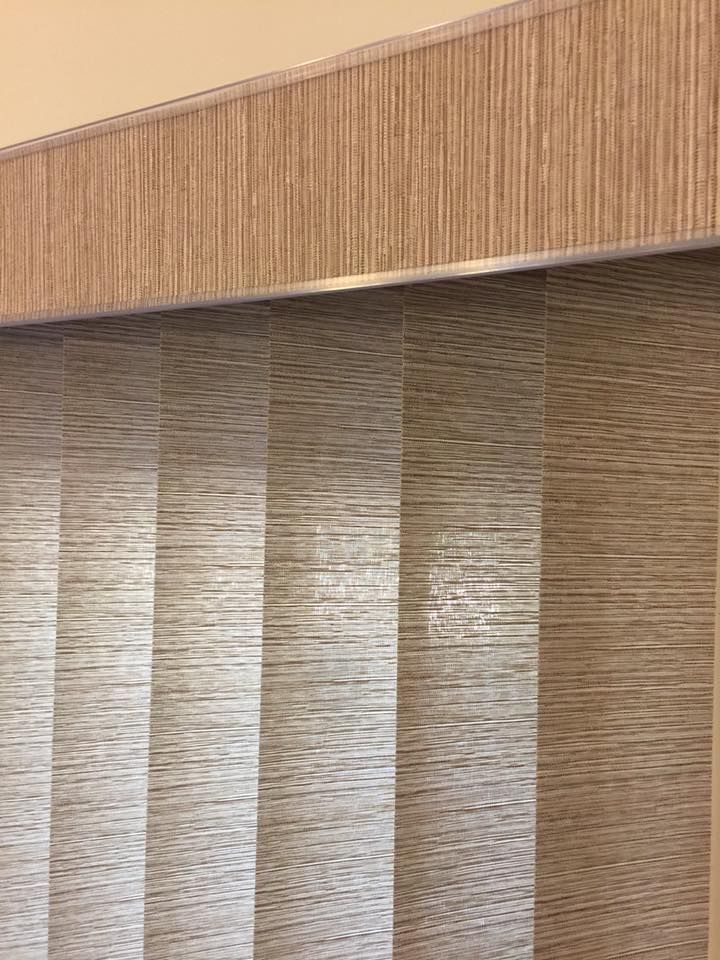 Vertical window blinds, light brown, with a matching valance above.