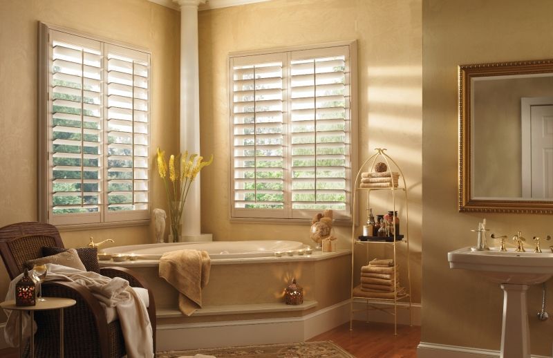 Bathroom with bathtub, shutters, gold accents, and a vanity.