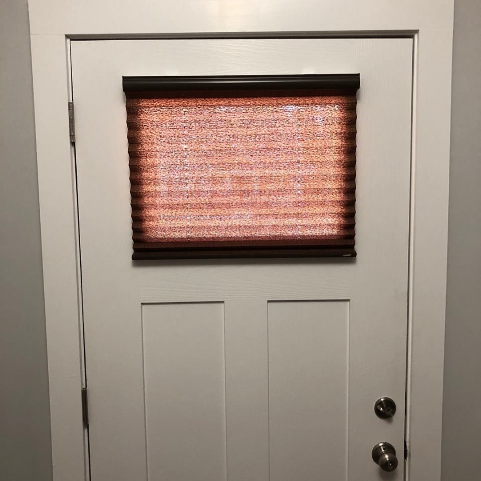 White door with a window and a red pleated shade.