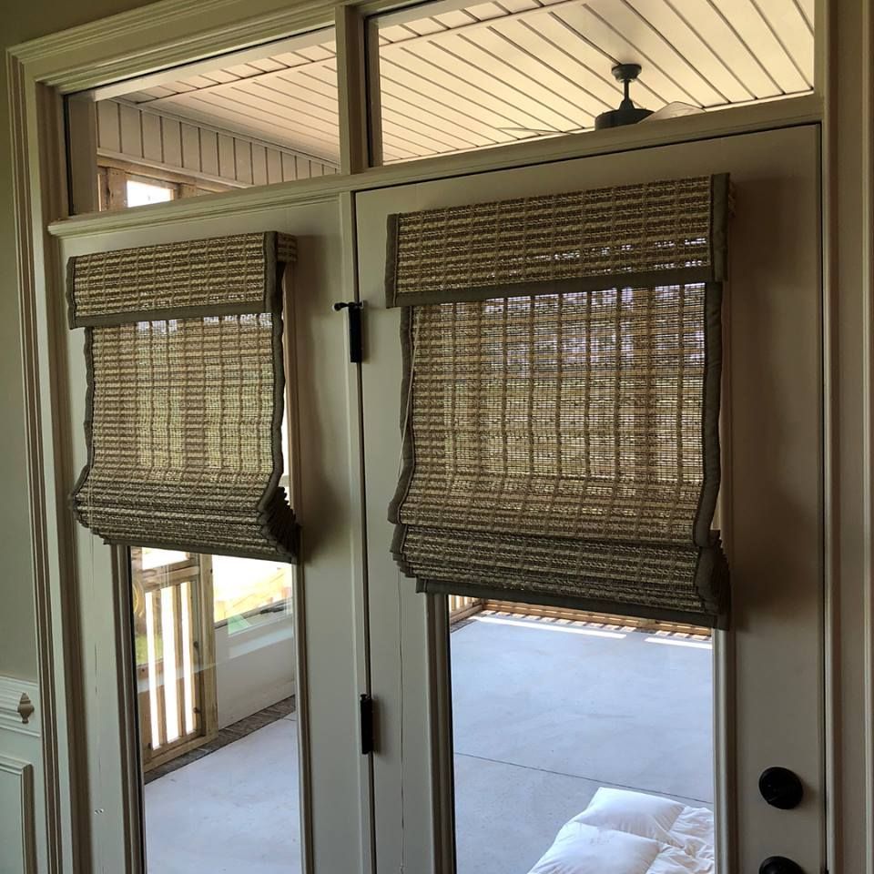 Two doors with woven shades, looking out to a patio.