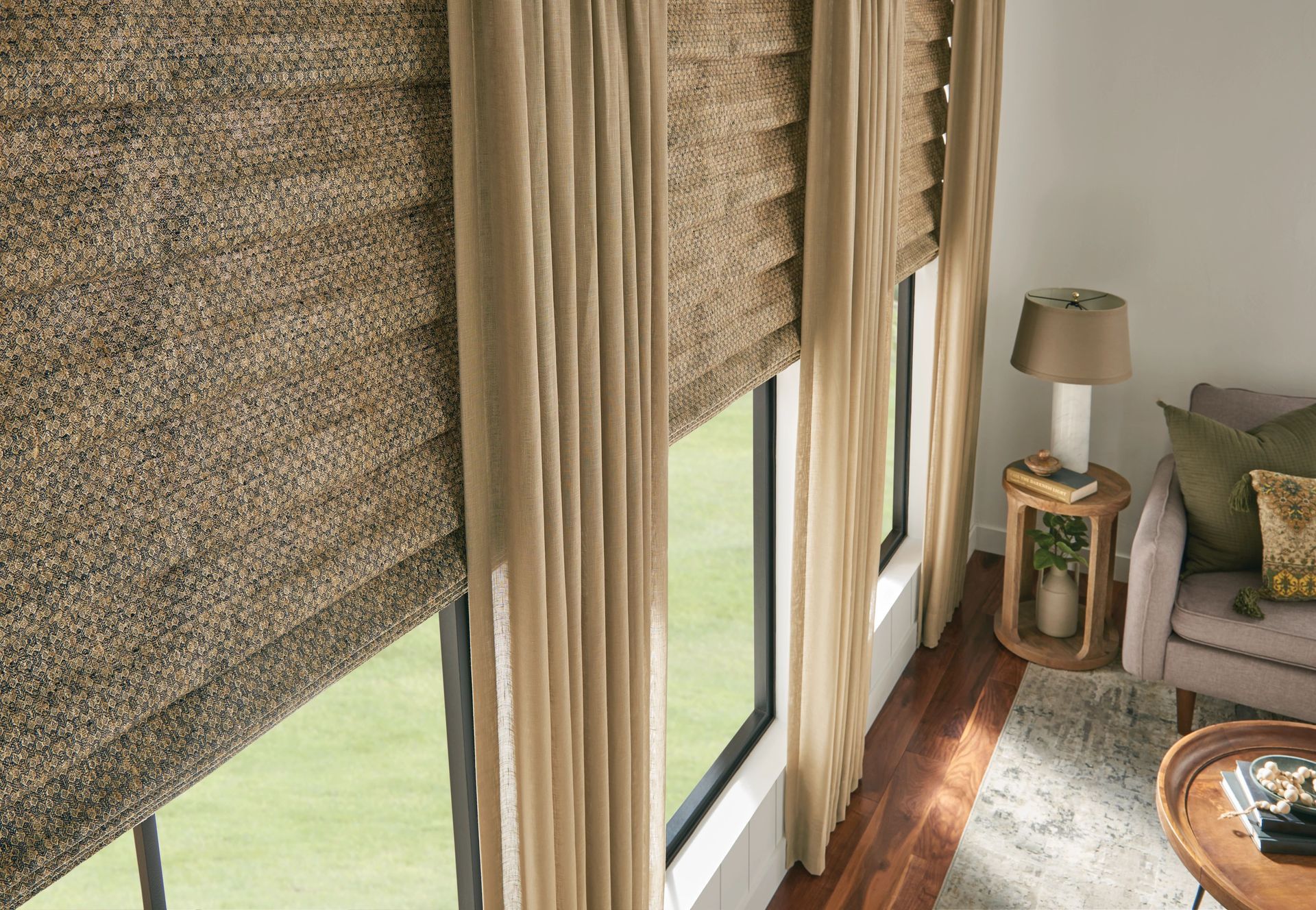 Window with layered shades and curtains; a room with natural light and a seating area.