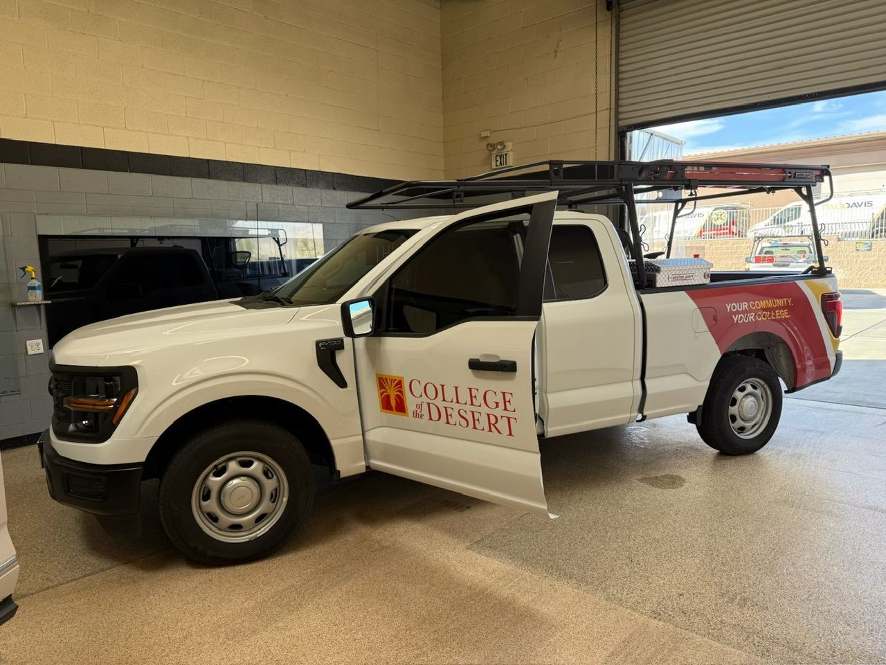 White pickup truck with College Ministry logo parked in a garage. Door open.