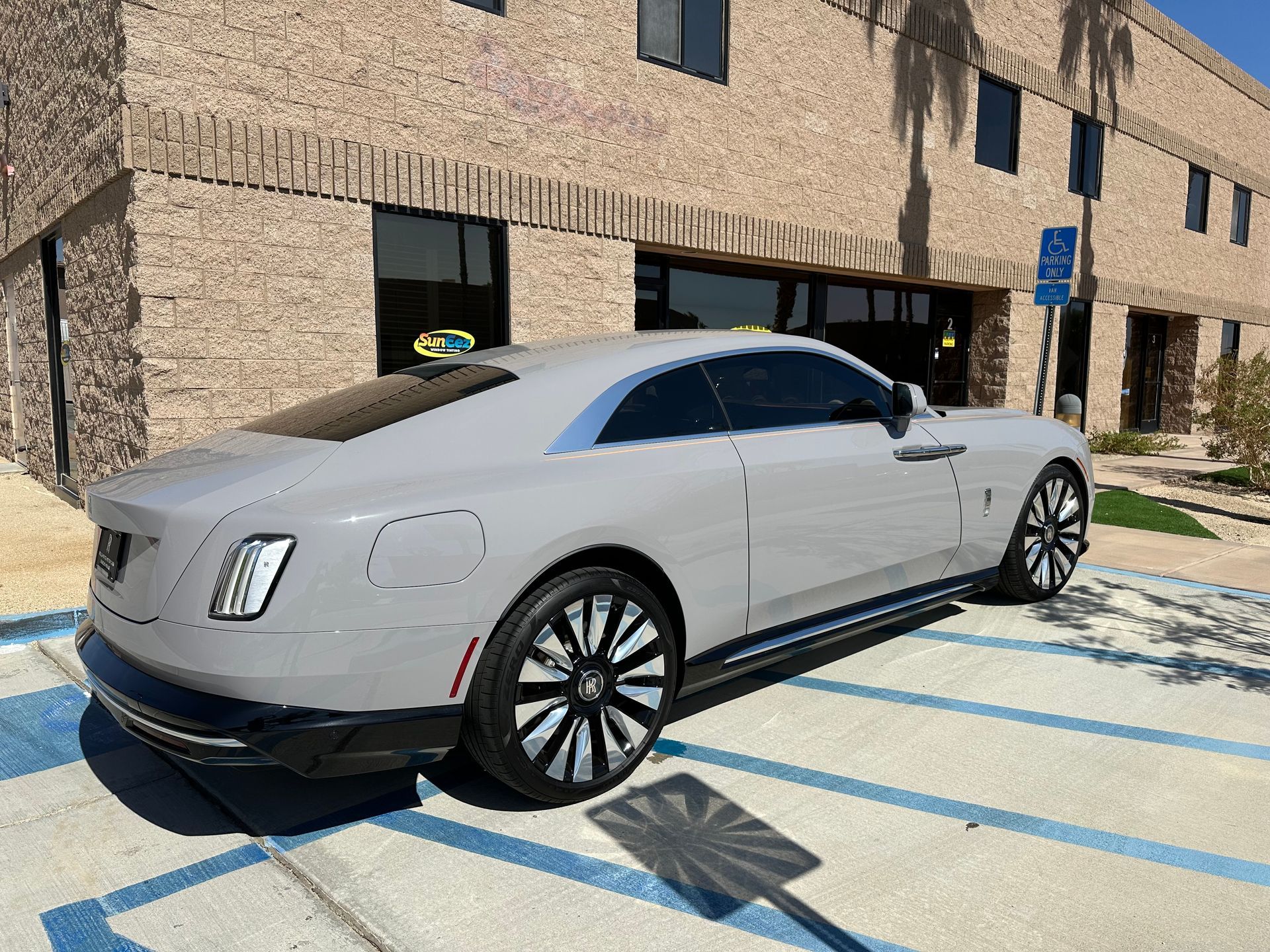 A gray car is parked in a parking lot in front of a building.