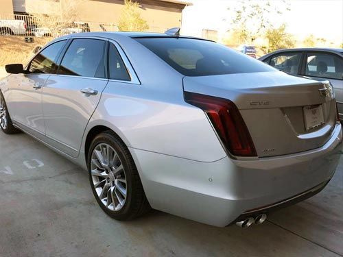 A silver cadillac is parked in a parking lot.