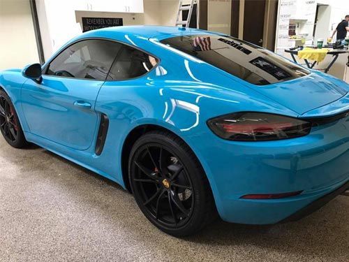 A blue porsche boxster is parked in a garage.