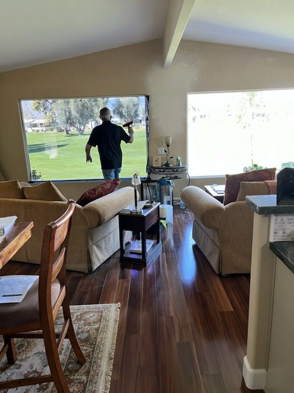 A man is cleaning a window in a living room.