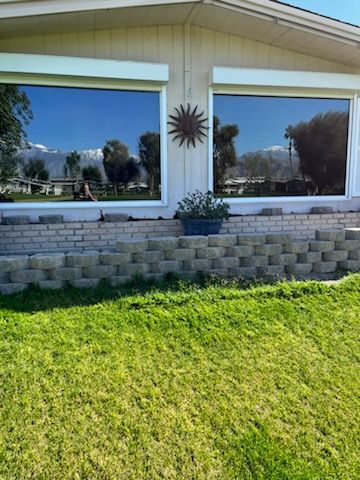 A house with a lot of windows and a large lawn in front of it.
