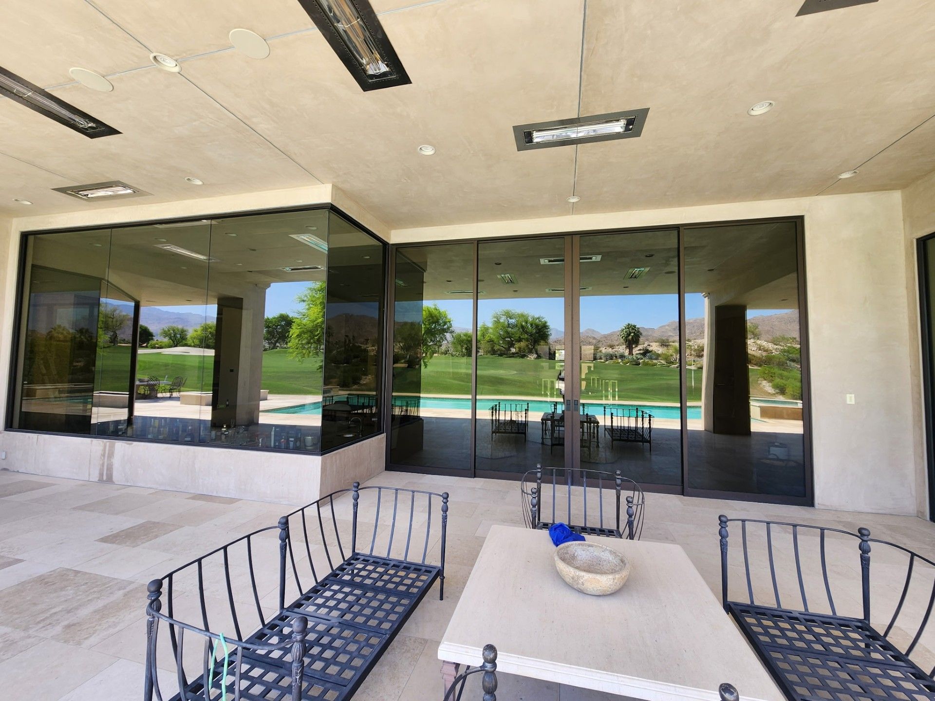 A patio with a table and chairs and a pool in the background