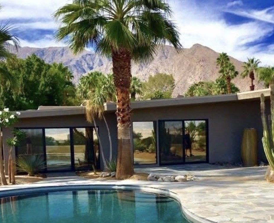 A house with a pool and palm trees in front of it