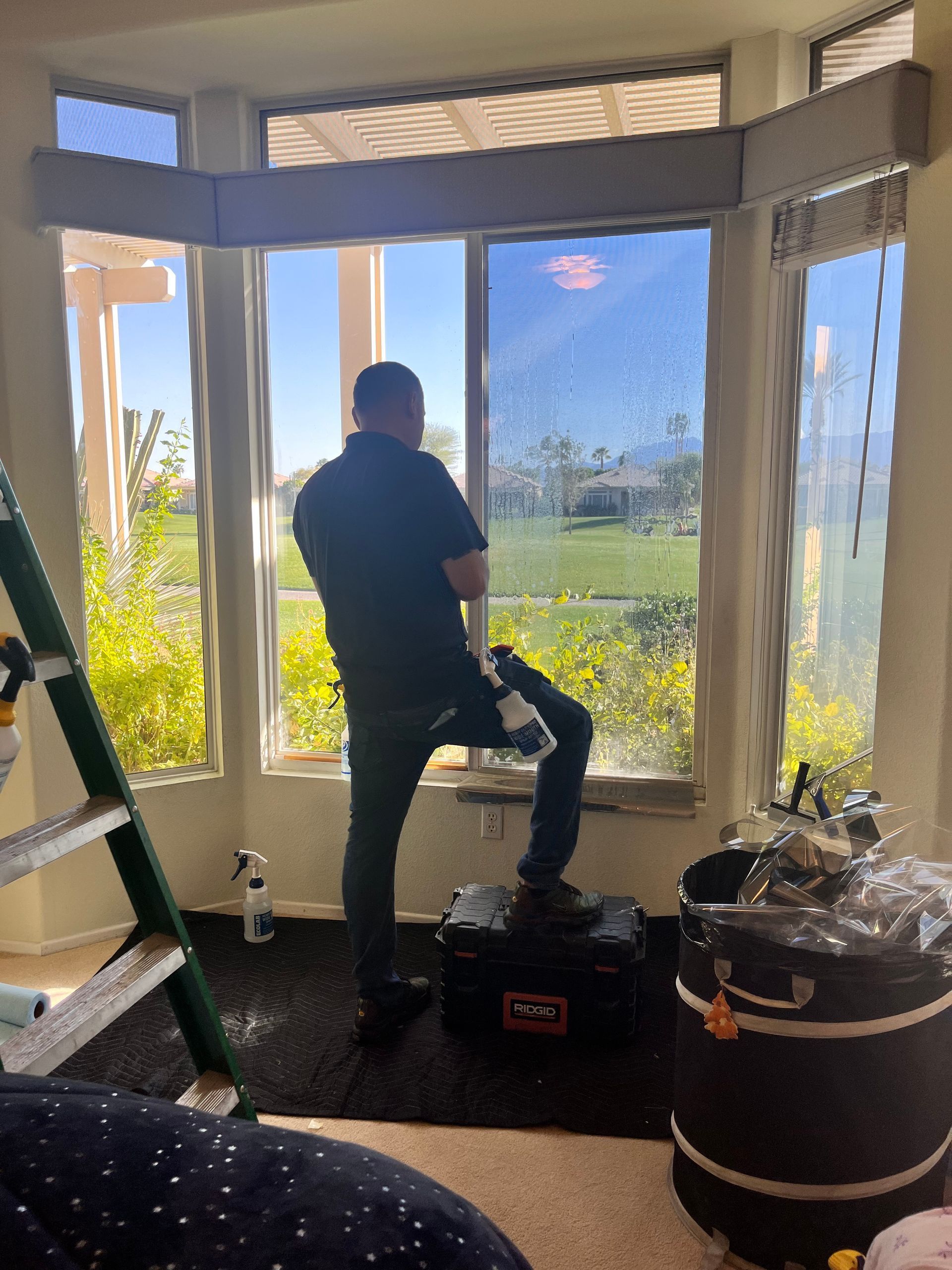 A man is sitting on a stool in front of a window.