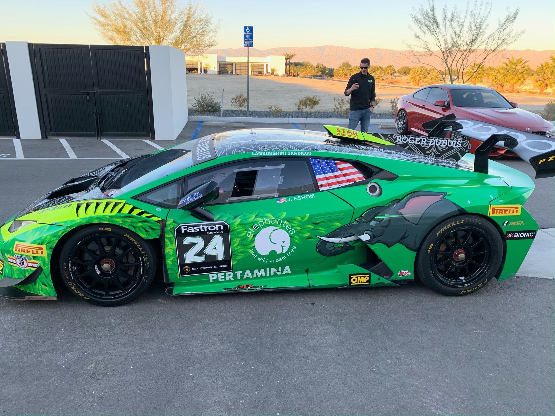 A green race car with the number 24 on the side is parked in a parking lot.