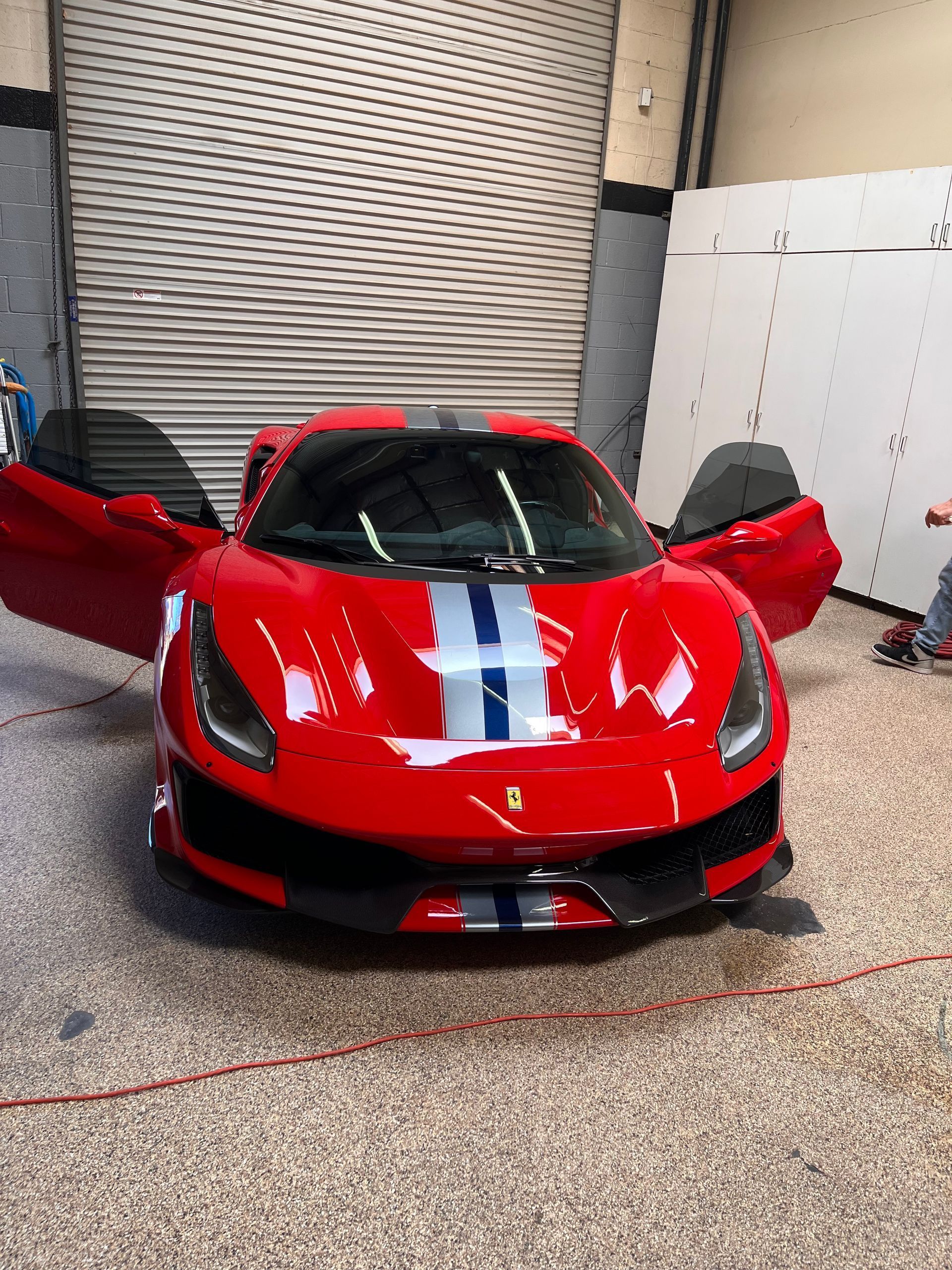 A red sports car is parked in a garage with its doors open.